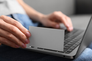 Woman with laptop holding blank business card, closeup. Space for text