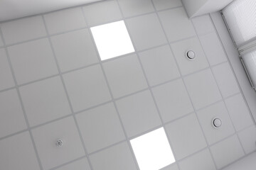 White ceiling with PVC tiles and lighting indoors, bottom view