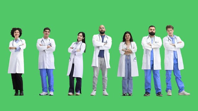 A group of doctors, on a green background, in full height, crossed their arms