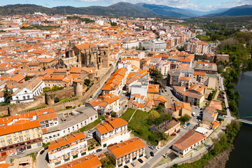 Fototapeta na wymiar Picturesque aerial view of Plasencia city located in valley of Jerte river overlooking terracotta tiled roofs of residential buildings and medieval cathedral complex in spring, Extremadura, Spain