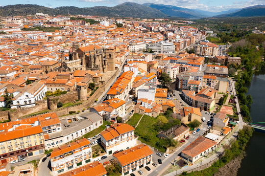 Picturesque aerial view of Plasencia city located in valley of Jerte river overlooking terracotta tiled roofs of residential buildings and medieval cathedral complex in spring, Extremadura, Spain