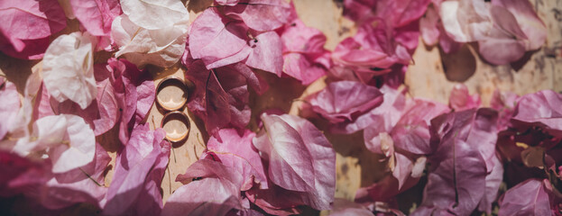 Bride's morning and wedding details. Wedding gold rings on a stone surface in bougainvillea flowers
