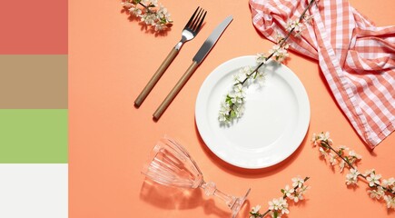 Beautiful table setting with blossoming branches on orange background. Different color patterns