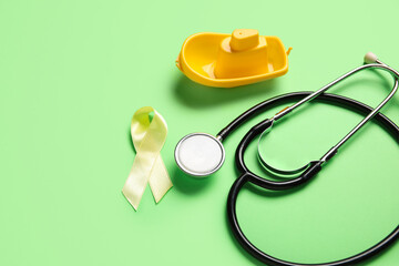 Golden ribbon with stethoscope and toy boat on green background. Childhood cancer awareness concept