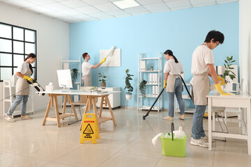 Group of young janitors cleaning in office