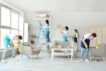 Group of young janitors cleaning in room