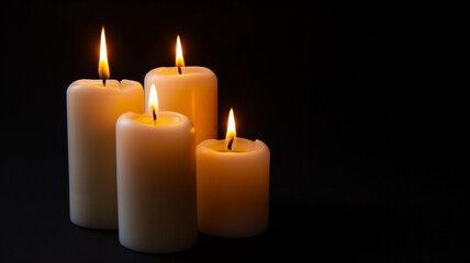 Fototapeta na wymiar Four lit candles in the dark, glowing with a tranquil and serene light.