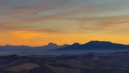 Deurstickers Luminoso tramonto arancio e ocra sopra le montagne italiane © GjGj