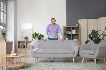 Young man behind grey sofa at home