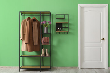 Stylish hallway interior with clothes rack, shelf and spring flowers