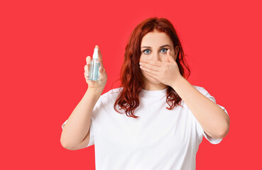 Beautiful young woman with bottle of sanitizer on red background