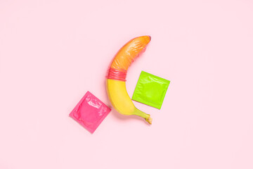 Condoms and banana on pink background. Sex education - obrazy, fototapety, plakaty