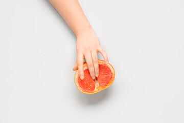 Female hand with fresh grapefruit on white background. Sex education