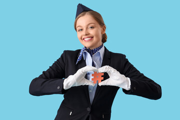 Young stewardess with hashtag sign making heart gesture on blue background
