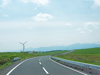 Travelling on rural Kyushu, driving to distant Mount Aso volcano caldera by lonely road through the green valley with wind turbine on sunny day