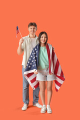 Young couple with flags of USA on orange background