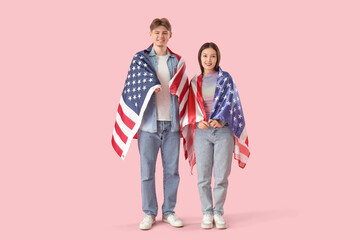 Young couple with flags of USA on pink background