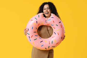 Happy female office worker with inflatable ring on yellow background. Summer vacation concept - obrazy, fototapety, plakaty