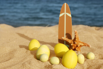 Surfboard, starfish and painted Easter eggs on sea beach