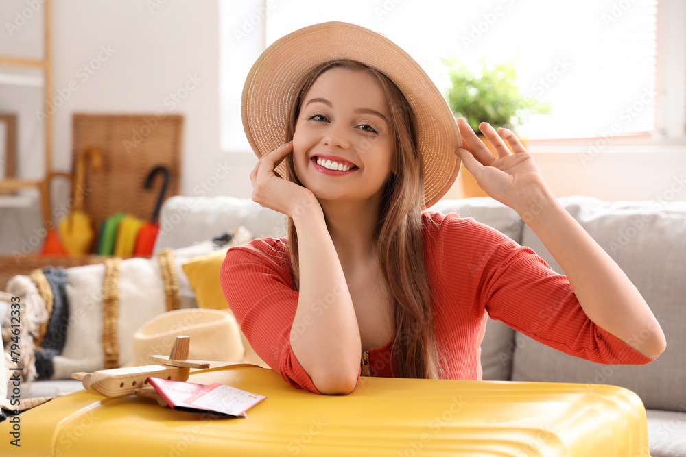 Wall mural Young woman with packed suitcase for vacation at home