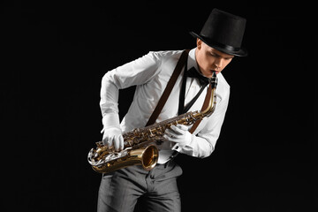 Naklejka premium Male artist playing saxophone on black background