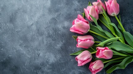 A stunning bouquet of pink tulip flowers is elegantly presented on a sleek gray backdrop in a top down flat lay style embodying a vibrant spring floral theme