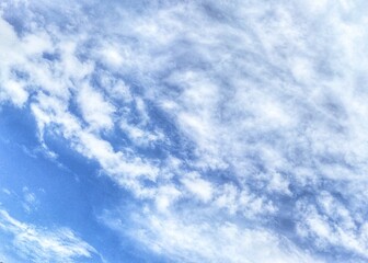 The view of white cirrus clouds against a bright blue sky background.