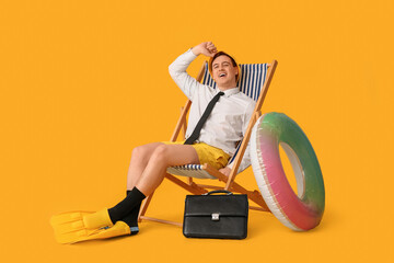Office worker with inflatable ring and flippers sitting on deck chair and dreaming about vacation...