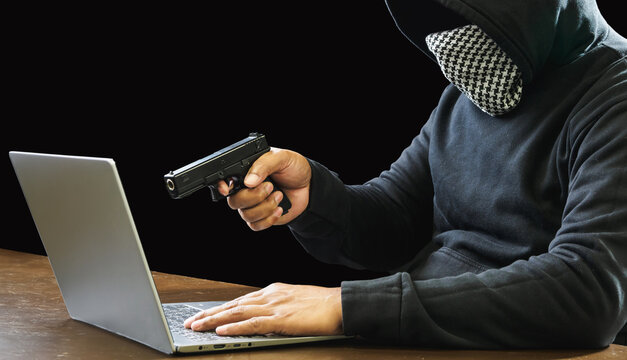 Portrait hacker spy man one person in black hoodie sitting on table looking computer laptop used login password attack security to data digital internet network system night dark background copy space