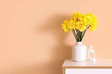 Vase with daffodil flowers on chest of drawers in living room
