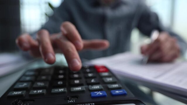 accountant working on desk using calculator for calculate finance report in office