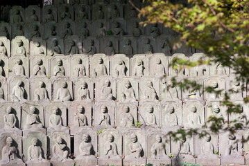 A wall of statues of people, some of which are of Buddha