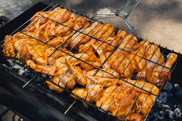 BBQ picnic time Roasted chicken legs and wings on grill. Grilling meat on outdoor grill grid tasty barbeque chicken steak with smoke flames juicy meat in the backyard in summer
