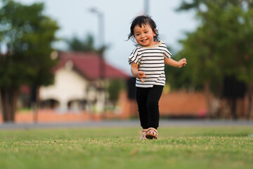 happy toddler girl running on grass field in park