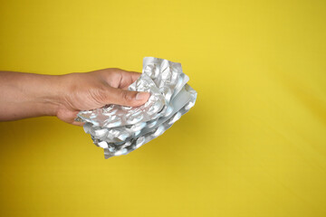  holding empty pills of blister pack on yellow background 