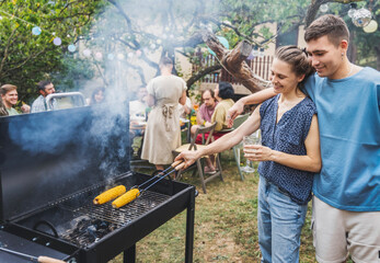 Couple of young adult friends friends cooking barbecue grill at summer friendly garden party