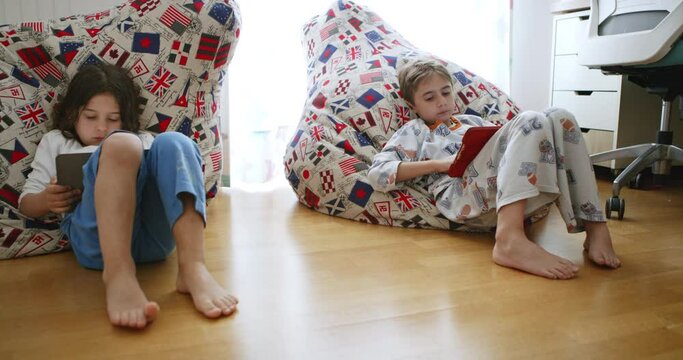 Boys lounges comfortably, intently focused on his brightly colored digital tablet.