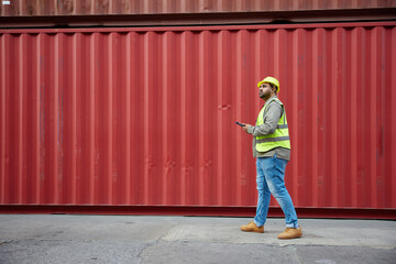 worker or engineer walking forward and working on tablet in containers warehouse storage