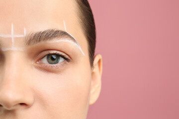 Eyebrow correction. Young woman with markings on face against pink background, closeup. Space for...