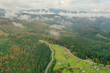 Aerial view of beautiful forest, road and mountain village on autumn day
