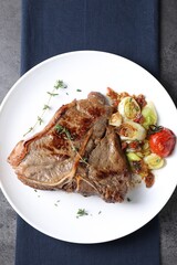 Delicious fried beef meat and vegetables on grey table, top view