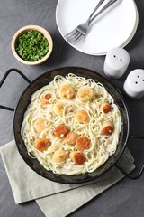 Delicious scallop pasta with green onion served on grey table, flat lay