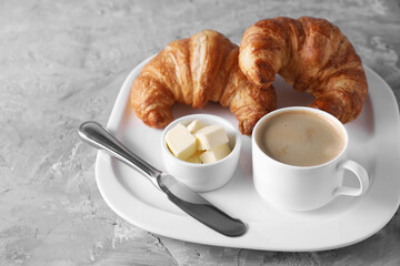 Tasty breakfast. Cup of coffee, fresh croissants, knife and butter on grey table, closeup