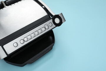 Electric grill on light blue background, above view. Space for text. Cooking appliance