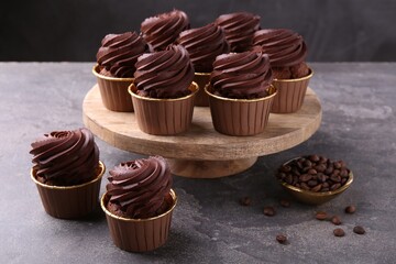 Delicious chocolate cupcakes and coffee beans on grey textured table