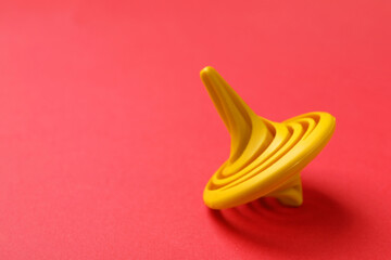 One yellow spinning top on red background, closeup. Space for text