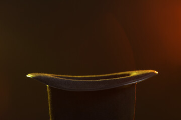 Black magician's hat on dark background, closeup. Space for text