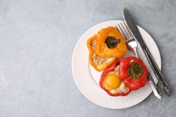 Delicious stuffed peppers with egg served on grey textured table, top view. Space for text