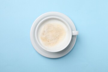 Aromatic coffee in cup on light blue background, top view