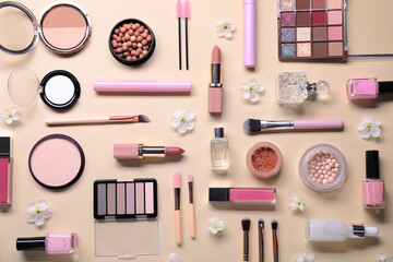Fototapeta premium Flat lay composition with different makeup products and beautiful spring flowers on beige background